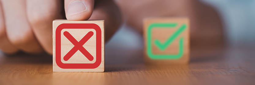 A hand is about to touch a wooden block with a red "X," next to another block with a green checkmark.